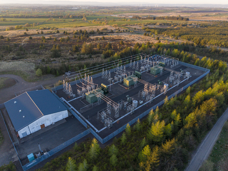 Aerial view of Eaglesham moor electrical substation with transformers and power lines surrounded by coniferous trees in Kilmarnock Scotland United Kingdom.