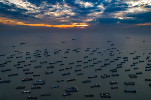 Chittagong Bangladesh 02 December 2023 Aerial view of numerous cargo ships anchored in the sea during a dramatic sunset with a cloudy sky.
