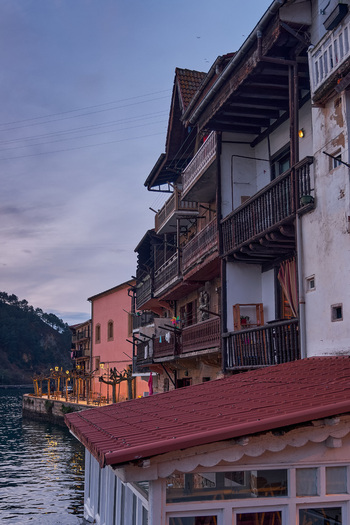Pasai Donibane Spain 09 March 2026 View of the main harbor street with traditional buildings featuring wooden balconies along the waterfront at dusk.