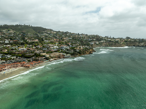 Aerial view of La Jolla Cove featuring turquoise ocean water breaking waves and coastal residences on the hillside in San Diego California United States. Aerial view of La Jolla Cove featuring turquoise ocean water breaking waves and coastal residences on the hillside in San Diego California United States.