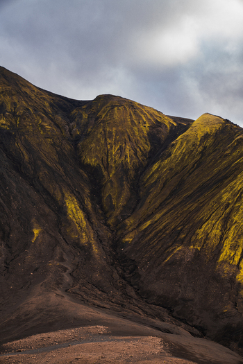 View of stark rugged mountainsides with vibrant green moss clinging to the steep slopes under a cloudy sky Skaftárhreppur Skaftárhreppur Iceland. View of stark rugged mountainsides with vibrant green moss clinging to the steep slopes under a cloudy sky Skaftárhreppur Skaftárhreppur Iceland.