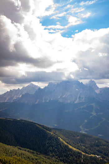 Aerial view of the Dolomites mountain range with dramatic clouds over the peaks and forested slopes in Rocca Pietore Veneto Italy.