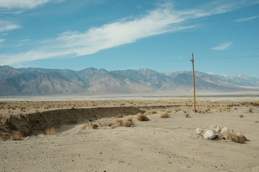 View of the rugged mountains and arid desert landscape of Death Valley with a utility pole under a blue sky Inyo County California United States. View of the rugged mountains and arid desert landscape of Death Valley with a utility pole under a blue sky Inyo County California United States.
