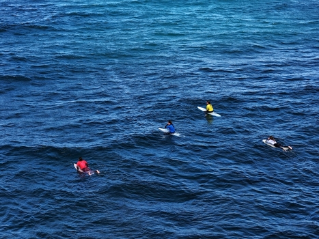 Aerial view of surfers waiting for waves in the deep blue waters of Praia do Areal de Santa Barbara in Ribeira Grande Acores Portugal. Aerial view of surfers waiting for waves in the deep blue waters of Praia do Areal de Santa Barbara in Ribeira Grande Acores Portugal.