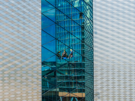 Vilnius Lithuania 20 April 2026 Aerial view of window cleaners suspended by ropes on the glass facade of a modern skyscraper in the city center. Vilnius Lithuania 20 April 2026 Aerial view of window cleaners suspended by ropes on the glass facade of a modern skyscraper in the city center.