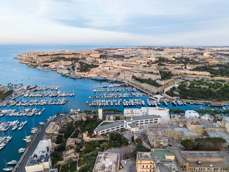 Aerial view of the historic city of Valletta and the harbor filled with white yachts and sailboats moored near stone fortifications in Malta. Aerial view of the historic city of Valletta and the harbor filled with white yachts and sailboats moored near stone fortifications in Malta.