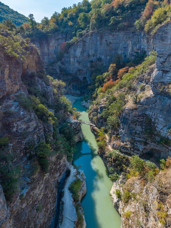 Aerial view of Osumi Canyon with its deep limestone cliffs turquoise river flowing through the gorge and lush green vegetation in Dhores Berat County Albania.