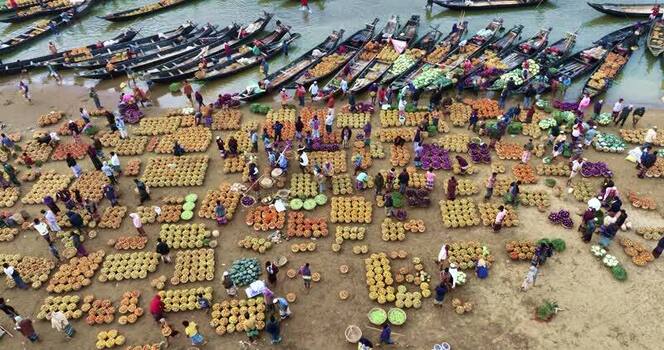 Aerial view of a busy riverside market with wooden boats Bangladesh.