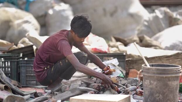 View of a young boy sorting recyclables in Bogura Bangladesh. View of a young boy sorting recyclables in Bogura Bangladesh.