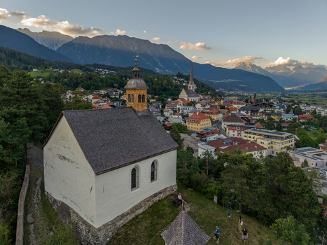 Aerial view of St. Laurentius Church in the foreground with the town of Imst and the surrounding Austrian Alps in the background Imst Tyrol Austria.