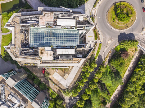 Aerial view of the modern office building on Lakeside Drive featuring a large glass atrium roof surrounding greenery and a nearby roundabout in London England United Kingdom. Aerial view of the modern office building on Lakeside Drive featuring a large glass atrium roof surrounding greenery and a nearby roundabout in London England United Kingdom.