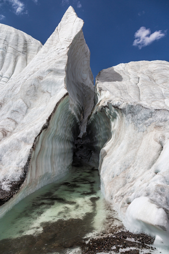 View of Baltoro Glacier featuring a deep crevasse with meltwater flowing through the ice set against a clear blue sky in Baltoro Gilgit Baltistan Pakistan.