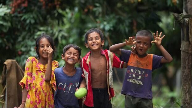 View of children laughing and playing in an orchard Bangladesh.