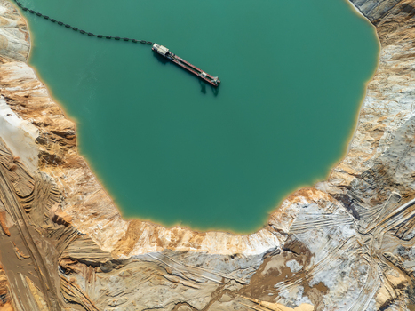 Aerial view of a dredging vessel floating in a turquoise mining pond surrounded by excavated sand and earth banks in Coimbra Coimbra District Portugal. Aerial view of a dredging vessel floating in a turquoise mining pond surrounded by excavated sand and earth banks in Coimbra Coimbra District Portugal.