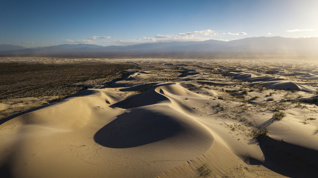 Aerial view of Dunas de Taton featuring vast sand dunes under a clear sky with distant mountains in Tinogasta Department Catamarca Province Argentina. Aerial view of Dunas de Taton featuring vast sand dunes under a clear sky with distant mountains in Tinogasta Department Catamarca Province Argentina.