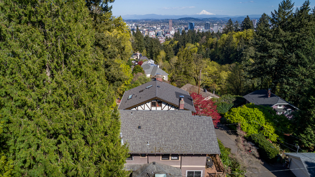 Aerial view of Northwest Imperial Terrace residential rooftops nestled among lush green trees with the Portland skyline and Mount Hood in the distance Portland Oregon United States. Aerial view of Northwest Imperial Terrace residential rooftops nestled among lush green trees with the Portland skyline and Mount Hood in the distance Portland Oregon United States.
