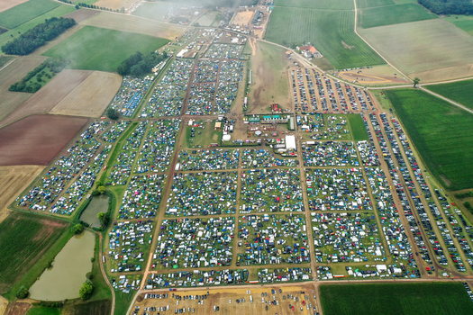 Aerial view of the Open Beatz Festival campsite featuring thousands of colorful tents and parking areas surrounded by green fields in Herzogenaurach Bayern Germany. Aerial view of the Open Beatz Festival campsite featuring thousands of colorful tents and parking areas surrounded by green fields in Herzogenaurach Bayern Germany.