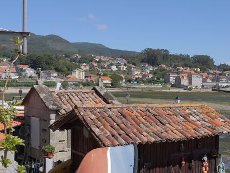 View of traditional stone horreos with terracotta tiled roofs overlooking the coastal village of Combarro Pontevedra Spain.