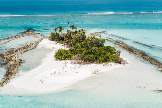 Aerial view of a lush tropical island with tall palm trees and dense vegetation surrounded by crystal clear turquoise lagoon water Innafinolhu Haa Alif Atoll Maldives. Aerial view of a lush tropical island with tall palm trees and dense vegetation surrounded by crystal clear turquoise lagoon water Innafinolhu Haa Alif Atoll Maldives.