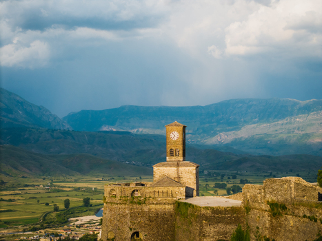 Aerial view of the historic Gjirokaster Castle featuring its iconic clock tower and stone fortifications overlooking the valley and mountains in Gjirokaster Gjirokaster County Albania. Aerial view of the historic Gjirokaster Castle featuring its iconic clock tower and stone fortifications overlooking the valley and mountains in Gjirokaster Gjirokaster County Albania.