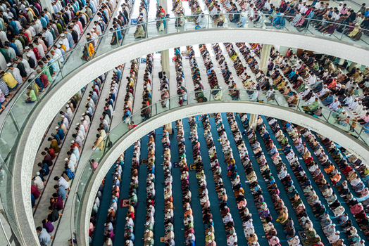 Dhaka Bangladesh 19 June 2026 Aerial view of a large congregation of people praying inside a modern mosque with multiple levels and curved balconies.