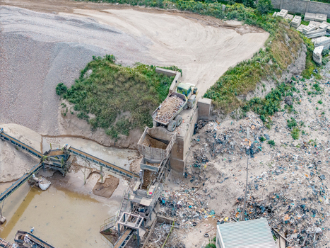 Aerial view of the Philippi industrial site with a dump truck unloading material into a conveyor system surrounded by piles of sand and gravel in Cape Town Western Cape South Africa.