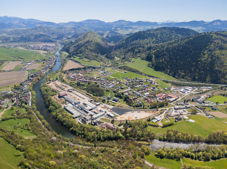 Aerial view of the Orava river winding past industrial facilities and residential houses nestled among the green hills of Oravsky Podzamok Zilina Region Slovakia. Aerial view of the Orava river winding past industrial facilities and residential houses nestled among the green hills of Oravsky Podzamok Zilina Region Slovakia.