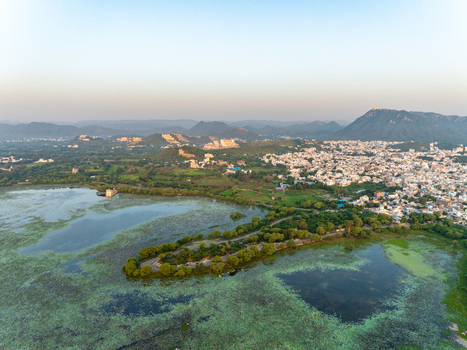 Aerial view of the scenic Fateh Sagar Lake surrounded by lush greenery hills and the urban landscape of Udaipur Rajasthan India.