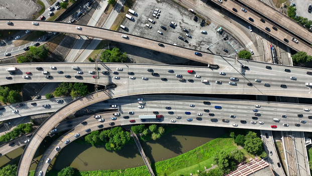 Aerial view of the complex highway interchange in Houston with heavy traffic flowing across multiple concrete lanes and surrounding green spaces in Harris County Texas United States.