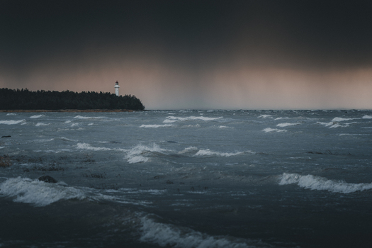View of Saxby Lighthouse standing on the coast amidst a stormy sea with dark clouds and crashing waves in Saxby Laane maakond Estonia.