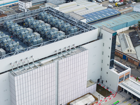 Aerial view of a modern data center featuring numerous rooftop cooling units industrial architecture and surrounding infrastructure in the United Kingdom. Aerial view of a modern data center featuring numerous rooftop cooling units industrial architecture and surrounding infrastructure in the United Kingdom.