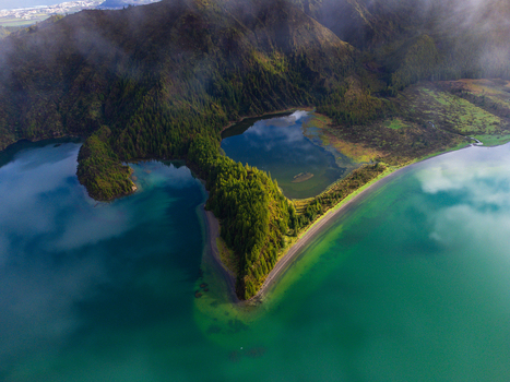 Aerial view of the Lagoa do Fogo crater lake with turquoise waters and lush green volcanic slopes under a misty sky in Agua de Alto Azores Portugal. Aerial view of the Lagoa do Fogo crater lake with turquoise waters and lush green volcanic slopes under a misty sky in Agua de Alto Azores Portugal.