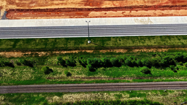 Aerial view of parallel railway tracks running through a green landscape with a construction zone and bare earth in Latvia. Aerial view of parallel railway tracks running through a green landscape with a construction zone and bare earth in Latvia.