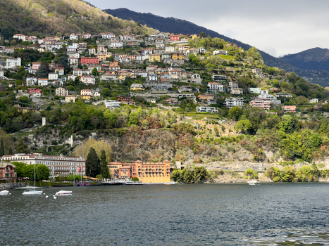 Aerial view of Villa d Este and the colorful hillside houses overlooking Lake Como with lush green vegetation and boats moored near the shore Cernobbio Lombardia Italy. Aerial view of Villa d Este and the colorful hillside houses overlooking Lake Como with lush green vegetation and boats moored near the shore Cernobbio Lombardia Italy.