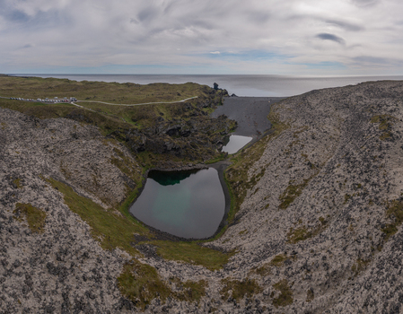 Aerial view of the black pebble beach at Djupalonssandur with a small lagoon rugged volcanic rock formations and mossy terrain along the coastline of Iceland. Aerial view of the black pebble beach at Djupalonssandur with a small lagoon rugged volcanic rock formations and mossy terrain along the coastline of Iceland.