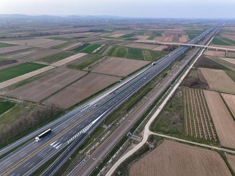 Aerial view of the A4 Torino Milano motorway and parallel railway line crossing agricultural fields with vehicles in transit Borgo d Ale Piedmont Italy. Aerial view of the A4 Torino Milano motorway and parallel railway line crossing agricultural fields with vehicles in transit Borgo d Ale Piedmont Italy.