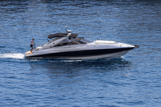 Aerial view of a sleek motorboat cruising on the deep blue Mediterranean sea near the coast of Monaco City with a person fishing from the stern in Monaco Monaco.
