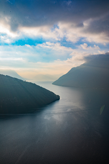 Aerial view of the Swiss Alps with a serene lake nestled between mountain slopes under a dramatic cloudy sky in Airolo Ticino Switzerland. Aerial view of the Swiss Alps with a serene lake nestled between mountain slopes under a dramatic cloudy sky in Airolo Ticino Switzerland.