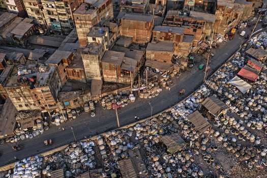 Aerial view of the Buriganga River area with dense urban buildings numerous piles of sacks along the road and small vehicles in Dhaka Dhaka Division Bangladesh. Aerial view of the Buriganga River area with dense urban buildings numerous piles of sacks along the road and small vehicles in Dhaka Dhaka Division Bangladesh.
