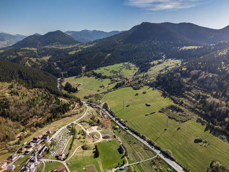 Aerial view of a traditional village nestled in a lush valley surrounded by the forested peaks of the Choc Mountains under a clear blue sky Valaska Dubova Zilina Region Slovakia. Aerial view of a traditional village nestled in a lush valley surrounded by the forested peaks of the Choc Mountains under a clear blue sky Valaska Dubova Zilina Region Slovakia.