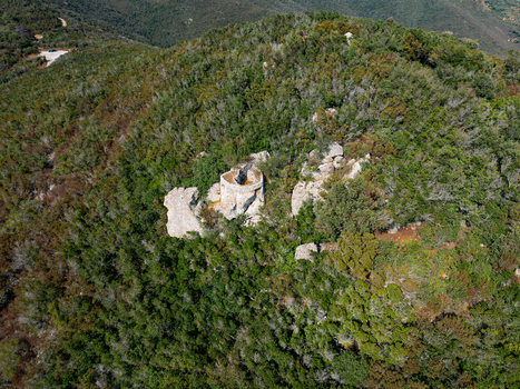 Aerial view of Passo del Monumento an ancient stone ruin nestled within a dense Mediterranean forest on a hillside Campo nell Elba Toscana Italy.