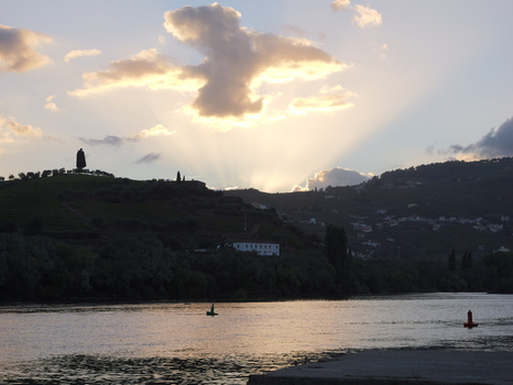 View of the sunset over the Douro River in Peso da Regua with a silhouette of a monument on the hillside vineyards Peso da Regua Vila Real District Portugal.