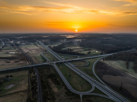 Aerial view of the A5 and A8 highway interchange at sunset featuring multi level roads surrounding fields and golden light in Olaine parish Olaine Municipality Latvia. Aerial view of the A5 and A8 highway interchange at sunset featuring multi level roads surrounding fields and golden light in Olaine parish Olaine Municipality Latvia.