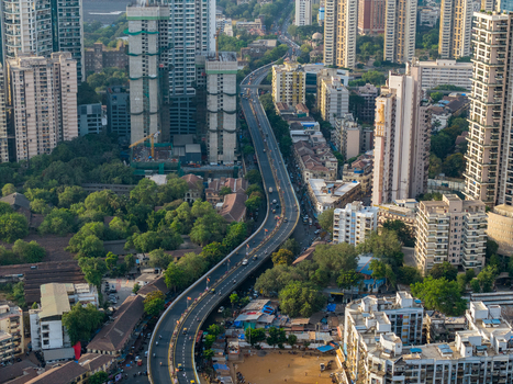 Aerial view of a winding elevated highway cutting through dense urban development with high rise buildings and lush green trees in Mumbai Maharashtra India. Aerial view of a winding elevated highway cutting through dense urban development with high rise buildings and lush green trees in Mumbai Maharashtra India.