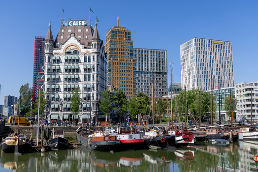 View of the historic Witte Huis building and traditional boats moored in the Oude Haven under a clear blue sky in Rotterdam South Holland Netherlands. View of the historic Witte Huis building and traditional boats moored in the Oude Haven under a clear blue sky in Rotterdam South Holland Netherlands.