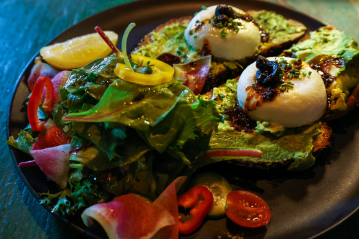 View of avocado toast with poached eggs and balsamic glaze served with a salad of greens tomatoes and radish at Ruba s Bakery Bistro San Jose del Cabo Baja California Sur Mexico.