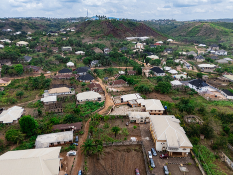 Aerial view of a residential area with varied roofs and winding roads blending into green hills under a cloudy sky ohafia Abia Nigeria. Aerial view of a residential area with varied roofs and winding roads blending into green hills under a cloudy sky ohafia Abia Nigeria.