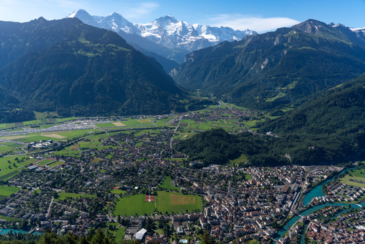 View of the town of Unterseen nestled in the valley with the Aare river surrounded by the majestic peaks of the Swiss Alps seen from Harder Kulm Unterseen Canton of Bern Switzerland.