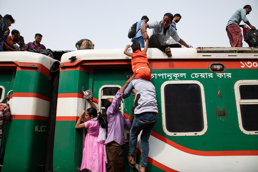Dhaka Bangladesh 14 June 2018 View of people and a child climbing onto the roof of a crowded train at Airport Railway Station during the Eid al Fitr holiday rush. Dhaka Bangladesh 14 June 2018 View of people and a child climbing onto the roof of a crowded train at Airport Railway Station during the Eid al Fitr holiday rush.
