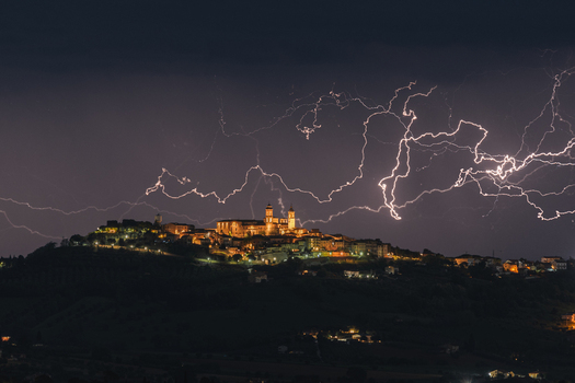 View of dramatic lightning strikes illuminating the night sky over the historic hilltop town of Montecosaro Marche Italy. View of dramatic lightning strikes illuminating the night sky over the historic hilltop town of Montecosaro Marche Italy.